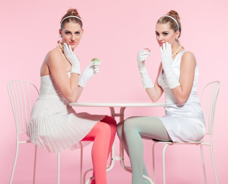 Two girls blonde hair fifties fashion style eating cup cake の写真素材