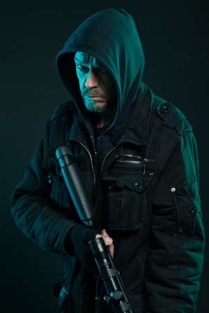 Sniper with beard in black holding gun. Studio shot.の写真素材