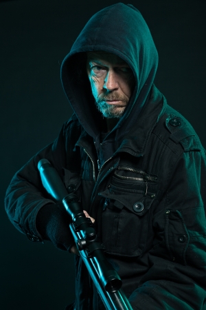 Sniper with beard in black holding gun. Studio shot.の写真素材