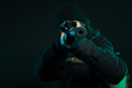 Sniper with beard in black holding gun. Studio shot.の写真素材