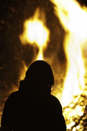 Silhouette of person in front of big campfire.の写真素材