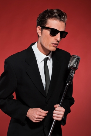 Retro fifties singer with vintage microphone and sunglasses. Studio shot.の写真素材