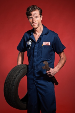 Retro fifties male car mechanic holding tool and tire. Studio shot.の写真素材