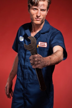 Retro fifties male car mechanic holding tool. Studio shot.の写真素材