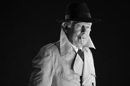 Retro mafia man with hat smoking cigarette. Black and white photo.