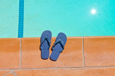 One pair of blue slippers on the edge of swimming pool.の写真素材