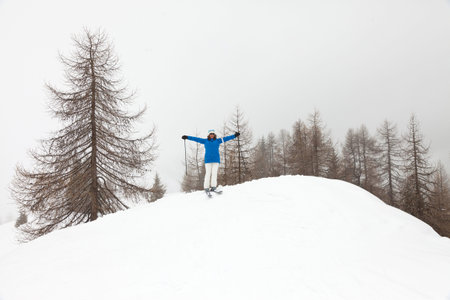 Happy ski woman standing in snow with pine trees.の写真素材