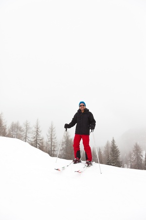 Happy ski man with blue hat standing in snow.の写真素材