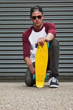 Hip cool urban fashion skateboarder with woolen hat on the street in front of iron wall.の写真素材