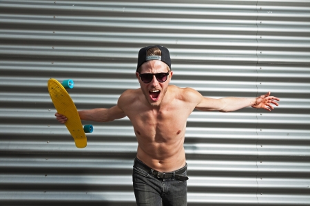 Rough cool street skateboarder with black cap and sunglasses in front of iron wall.の写真素材