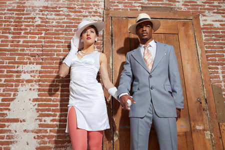 Vintage jazz fashion sexy wedding couple in old urban building. Mixed race. Wearing a hat.