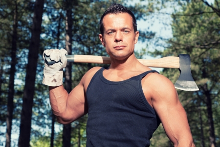 Muscled man with black shirt and axe in forest.の写真素材