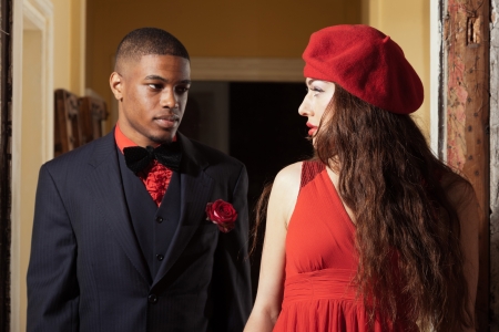 Vintage fashion mixed race wedding couple wearing black suit and red dress. Interior of old house.の写真素材