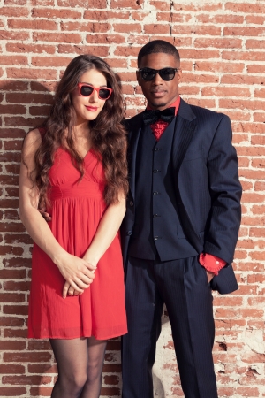 Urban cool retro fashion mixed race wedding couple wearing black suit and red dress and sunglasses.の写真素材