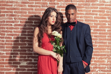 Urban cool vintage fashion mixed race wedding couple wearing black suit and red dress.の写真素材