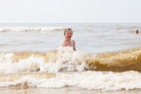 One young boy playing in the ocean with waves.の写真素材