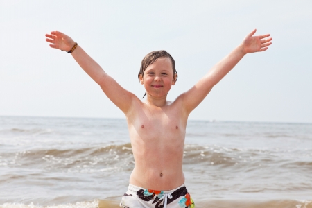 Kid boy having fun at the beach in the waves of the ocean.の写真素材