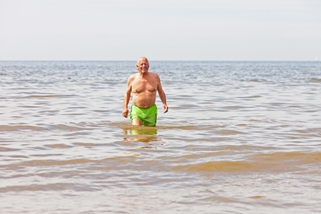 Single retired senior man enjoying the refreshment of the sea on a hot summer day  Blue cloudy sky の写真素材