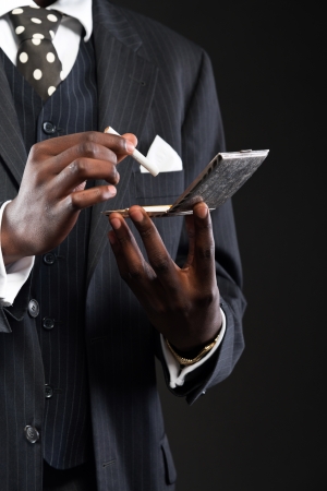 Close-up of hands of retro african american gangster man wearing striped suit and tie. Taking cigarette out of silver box. Studio shot.の写真素材