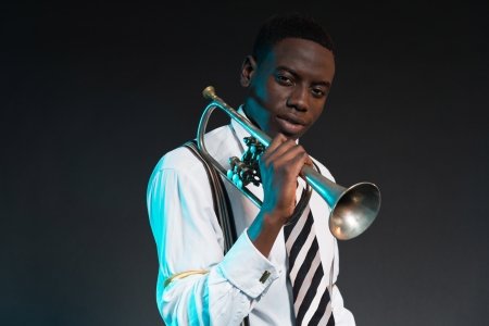 Retro african american jazz musician holding his trumpet. Wearing shirt and tie. Studio shot.の写真素材