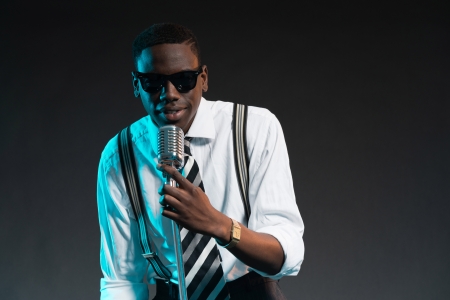 Retro african american jazz singer with microphone. Wearing shirt and tie and sunglasses. Studio shot.の写真素材