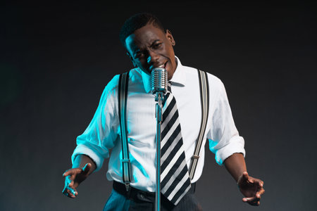 Retro african american jazz singer with microphone. Wearing shirt and tie. Studio shot.の写真素材