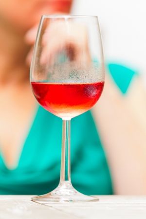 Glass of rose wine with blurred hand of a woman behind it.の写真素材