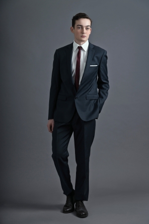 Retro fashion fifties young man wearing dark suit and tie. Studio shot against grey.の写真素材