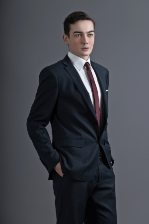 Retro fashion fifties young man wearing dark suit and tie. Studio shot against grey.の写真素材