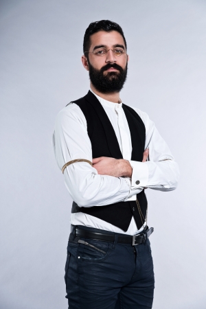 Retro hipster 1900 fashion man with black hair and beard. Wearing vintage glasses. Studio shot against grey.の写真素材