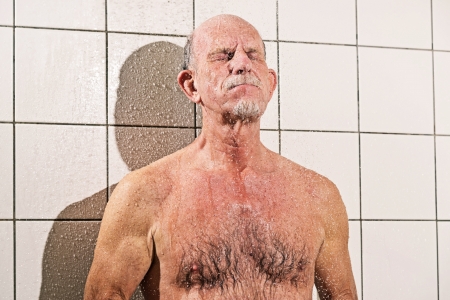 Senior man taking a shower in bathroom.の写真素材