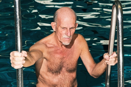 Senior man walking out of swimming pool.の写真素材