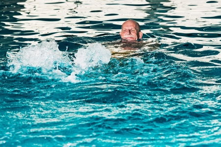Healthy senior man with beard in indoor swimming pool.の写真素材