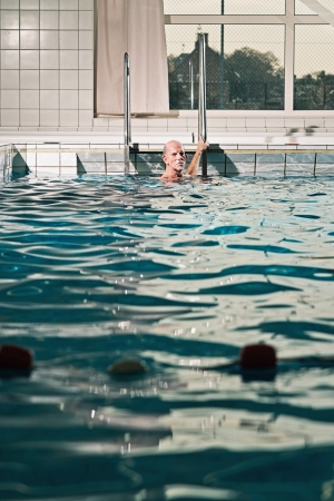 Healthy active senior man with beard in indoor swimming pool.の写真素材