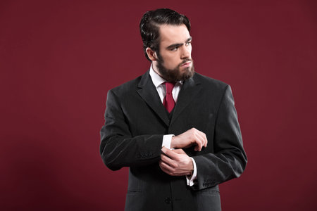 Retro 1900 fashion man with beard wearing grey suit and red tie. Studio shot.
