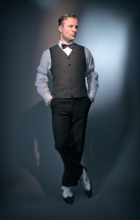 Retro classic business fashion man wearing grey gilet and bow tie. Studio shot. Retro classic business fashion man wearing grey gilet and bow tie. Studio shot.