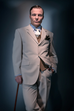 Retro 1920 business fashion man wearing white striped suit and tie. Standing with cane. Studio shot.の写真素材