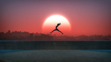 Silhouette of jumping ballet woman with skyline of skyscraper city in the background. Sunset with large sun. Rooftop of high building.の写真素材