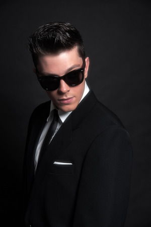 Retro fifties fashion man wearing black sunglasses with suit and tie. Studio shot.の写真素材