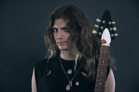 Male hard rock electric guitar musician with long hair. Studio shot against grey.