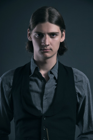 Western 1900 fashion man with brown hair. Studio shot against grey.の写真素材