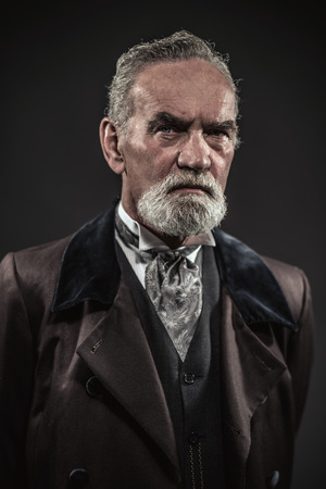 Vintage characteristic senior man with gray hair and beard. Studio shot against dark background.の写真素材