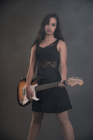Teenage rock girl with electric guitar. Wearing black dress.の写真素材