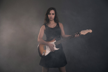 Teenage rock girl with electric guitar. Wearing black dress.の写真素材