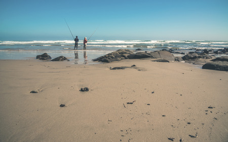 Two men fishing at the beach. Morgans Bay. Eastern Cape. South Africa.の写真素材
