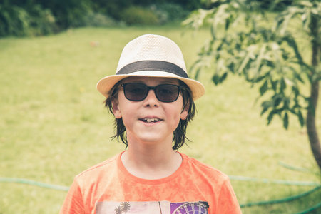 Teenage summer boy with hat and sunglasses in garden.の写真素材