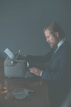 Handsome young businessman or business clerk sitting working at his desk typing on an old vintage...