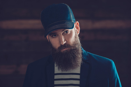 Close up Young Gorgeous Man in a Blue Cap with Long Beard and Mustache Looking at the Camera.の写真素材