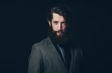 Close up Handsome Young Man with Long Goatee Beard, Wearing an Elegant Gray Business Coat, Looking...