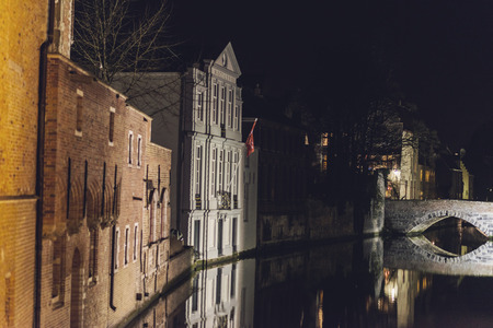 Traditional Architecture and Old Stone Arch Bridge over Canal Illuminated at Night in Bruges, Belgiumの写真素材